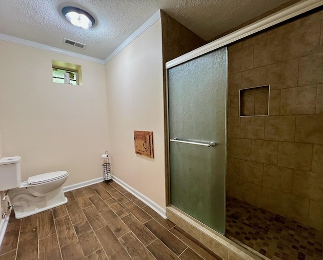 bathroom with a shower stall, visible vents, toilet, ornamental molding, and a textured ceiling