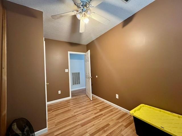 unfurnished bedroom with visible vents, light wood-type flooring, baseboards, a textured ceiling, and ceiling fan