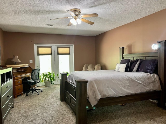 bedroom with a textured ceiling, visible vents, light carpet, and french doors