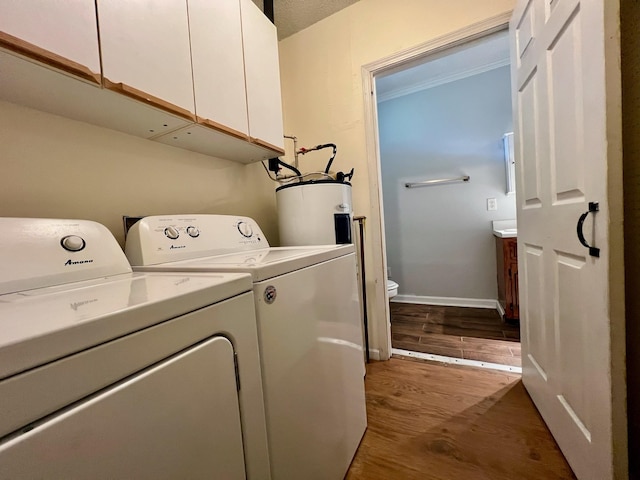 laundry area featuring separate washer and dryer, water heater, cabinet space, and wood finished floors