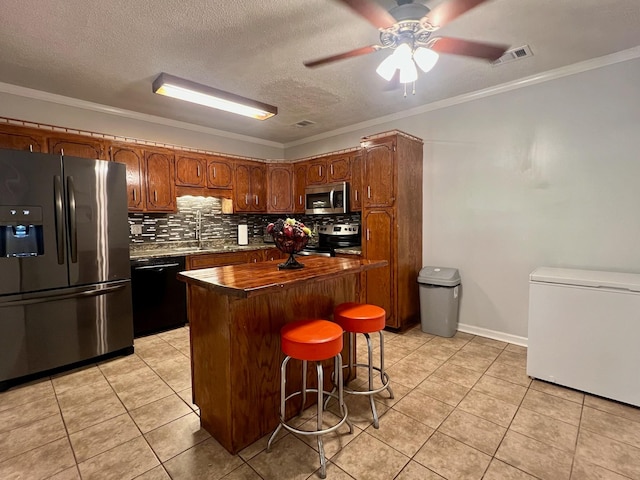 kitchen with backsplash, visible vents, light tile patterned floors, a center island, and appliances with stainless steel finishes