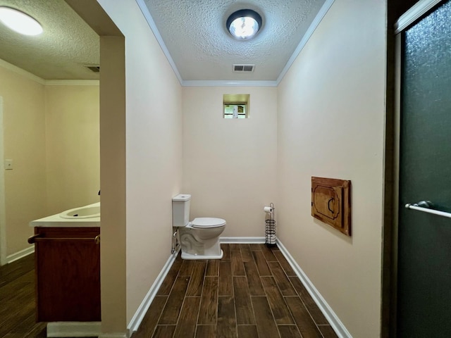 bathroom with a textured ceiling, wood finished floors, visible vents, and toilet
