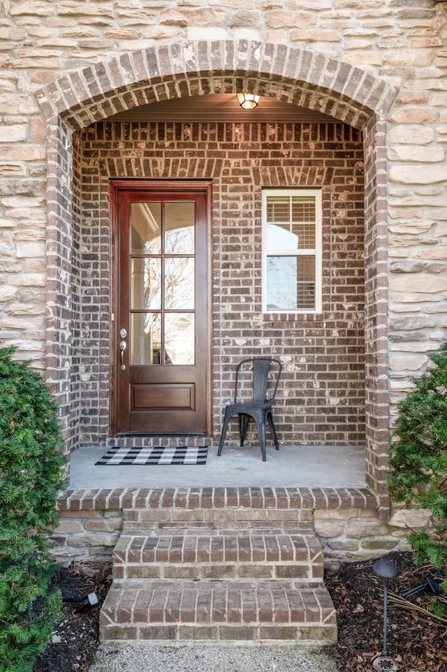 view of exterior entry featuring brick siding