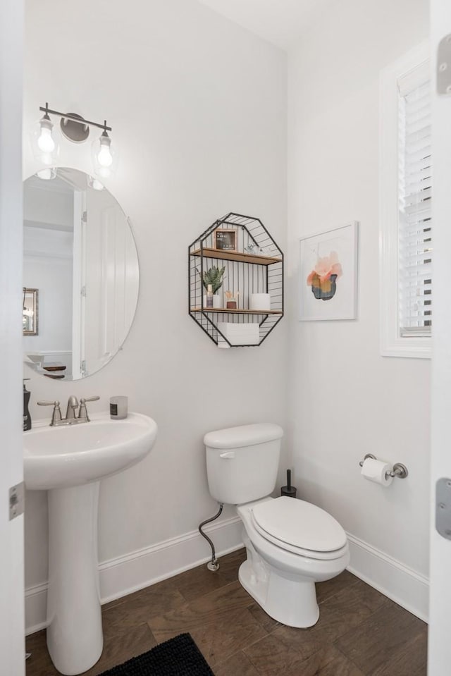 half bath featuring a sink, baseboards, and toilet