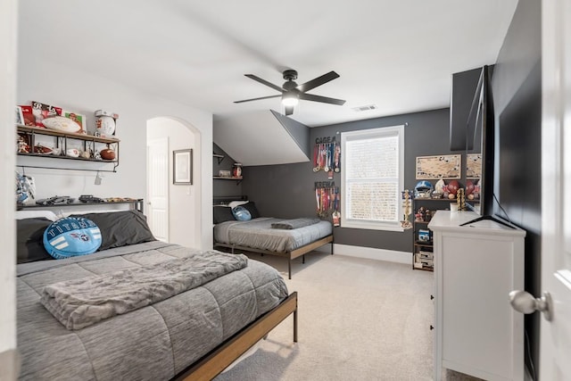 bedroom featuring visible vents, baseboards, ceiling fan, light colored carpet, and arched walkways