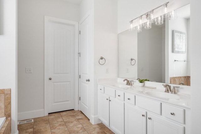 bathroom featuring double vanity, a relaxing tiled tub, visible vents, and a sink