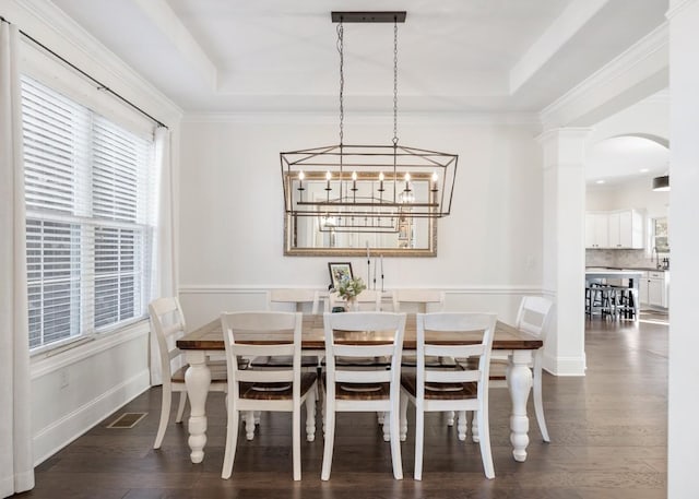 dining space featuring visible vents, baseboards, dark wood finished floors, arched walkways, and a raised ceiling