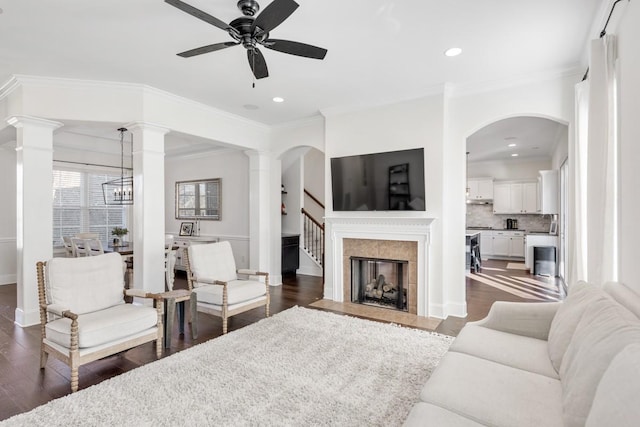 living room with a high end fireplace, dark wood-type flooring, ornate columns, and ornamental molding