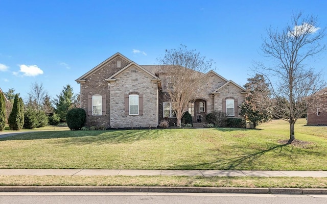 french provincial home featuring brick siding and a front lawn