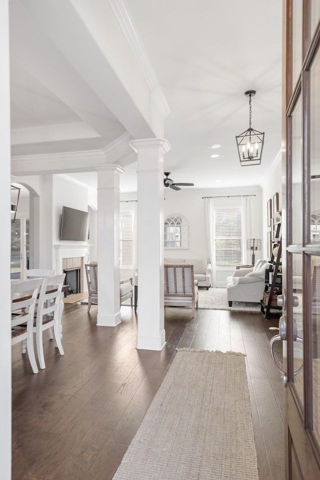 interior space featuring dark wood-type flooring, a fireplace, ornate columns, and ornamental molding