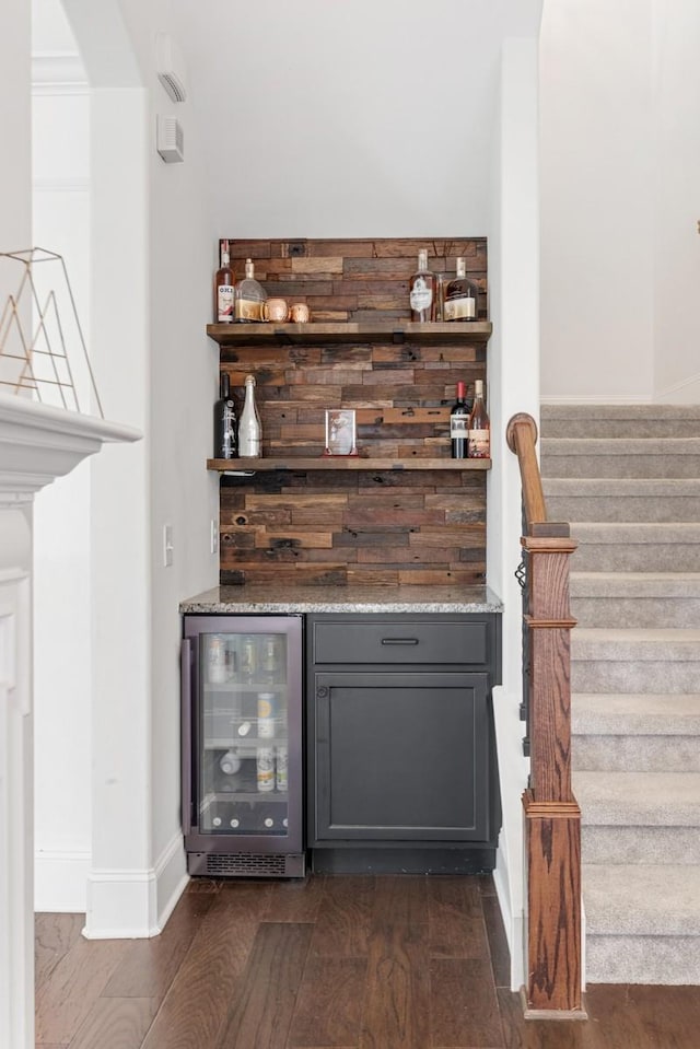 bar featuring stairway, wine cooler, a bar, and dark wood-style flooring