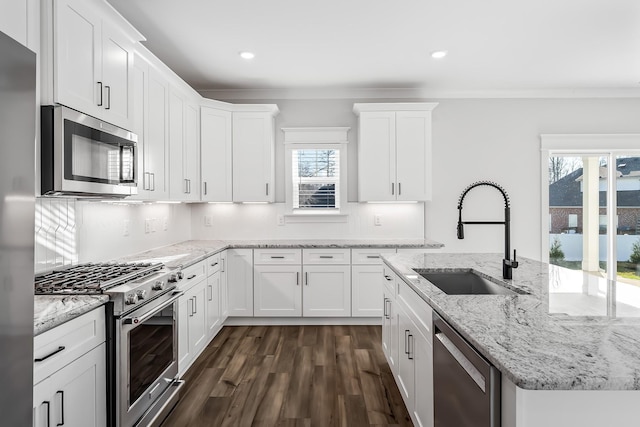 kitchen with a wealth of natural light, appliances with stainless steel finishes, white cabinetry, and a sink