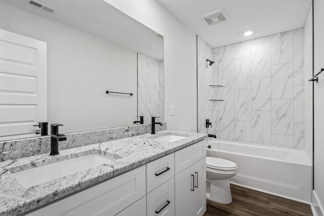 bathroom with visible vents, toilet, wood finished floors, and a sink