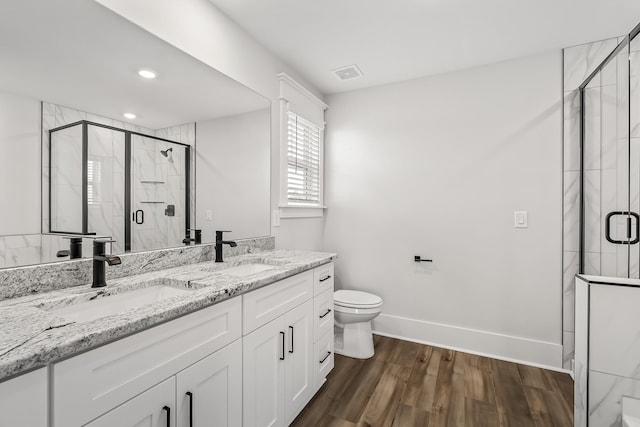 full bath with a stall shower, wood finished floors, visible vents, and a sink