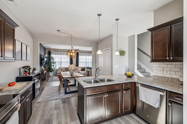 kitchen with light wood finished floors, dark brown cabinetry, dishwasher, a peninsula, and a sink