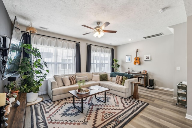 living area featuring a ceiling fan, baseboards, visible vents, and light wood-type flooring