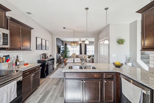 kitchen featuring visible vents, a sink, backsplash, dark brown cabinetry, and appliances with stainless steel finishes