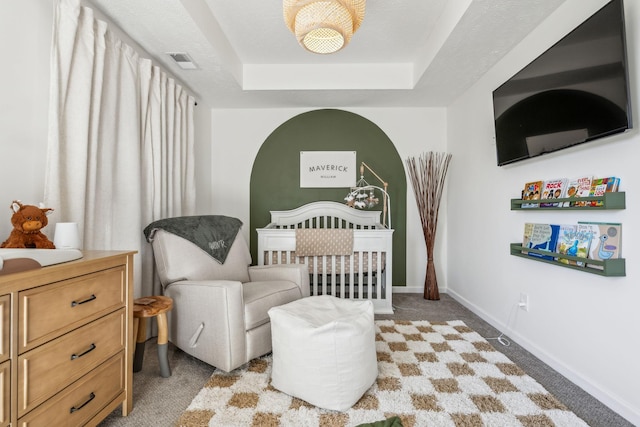 bedroom with visible vents, baseboards, light colored carpet, and a raised ceiling