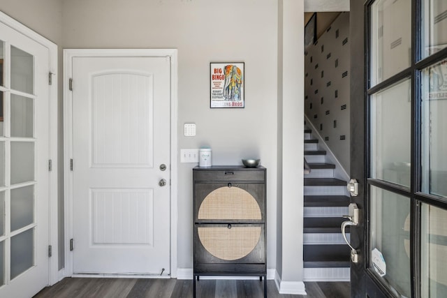 foyer with dark wood finished floors, stairway, and baseboards