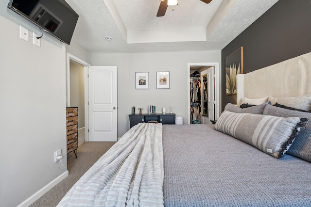 bedroom with a closet, carpet flooring, a walk in closet, and baseboards