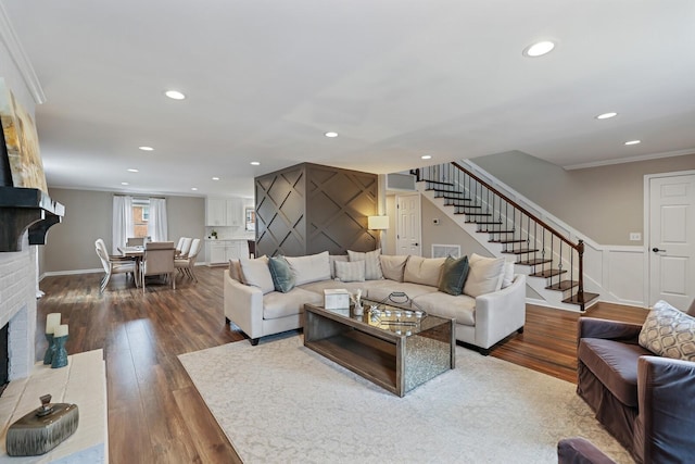 living room featuring dark wood finished floors, a fireplace, stairs, and ornamental molding