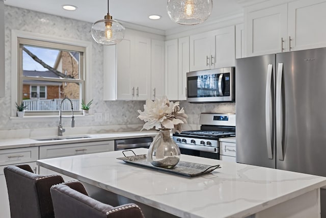 kitchen with a sink, a kitchen island, appliances with stainless steel finishes, and white cabinets