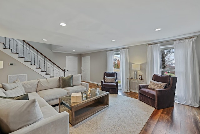 living area featuring a wealth of natural light, visible vents, wood finished floors, and stairs