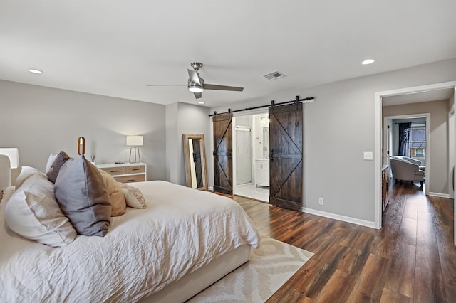 bedroom featuring a barn door, baseboards, visible vents, and wood finished floors