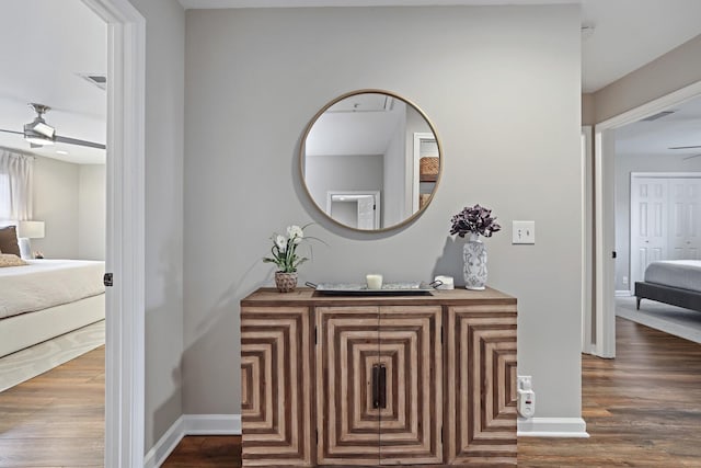 hall featuring visible vents, baseboards, and wood finished floors