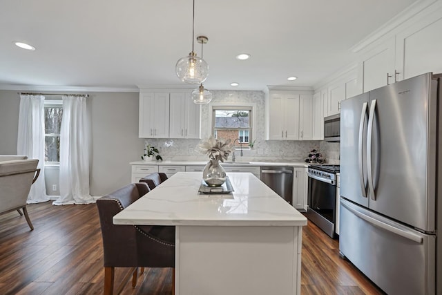 kitchen with dark wood-type flooring, a breakfast bar, a center island, appliances with stainless steel finishes, and white cabinets