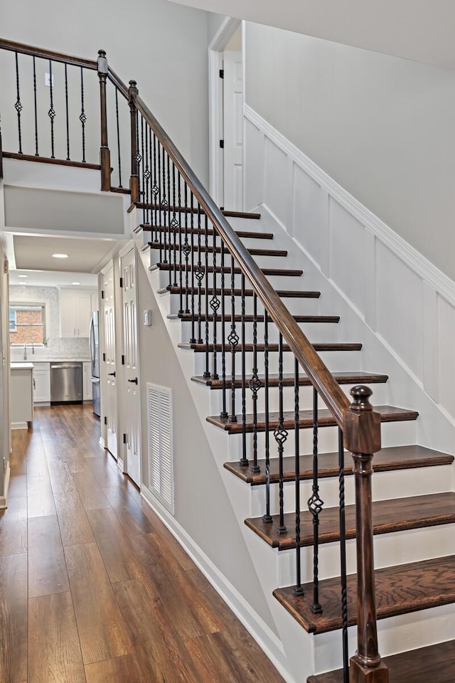 staircase with visible vents, a decorative wall, a wainscoted wall, and hardwood / wood-style floors