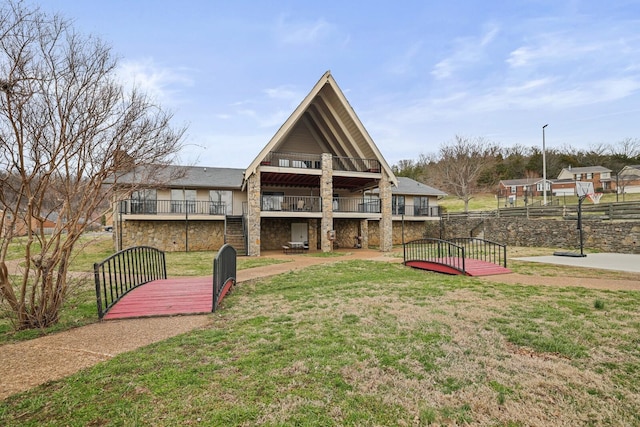 rear view of property featuring stone siding and a yard