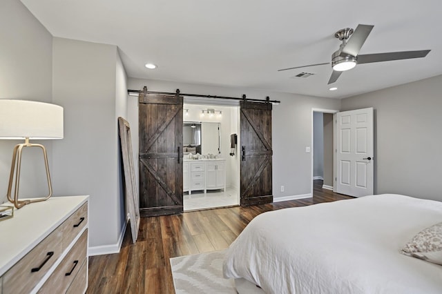 bedroom featuring a barn door, baseboards, visible vents, and dark wood-style flooring