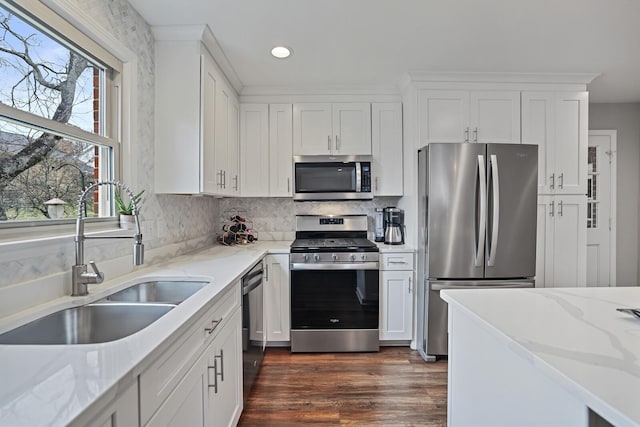 kitchen with dark wood-type flooring, a sink, white cabinetry, stainless steel appliances, and light stone countertops