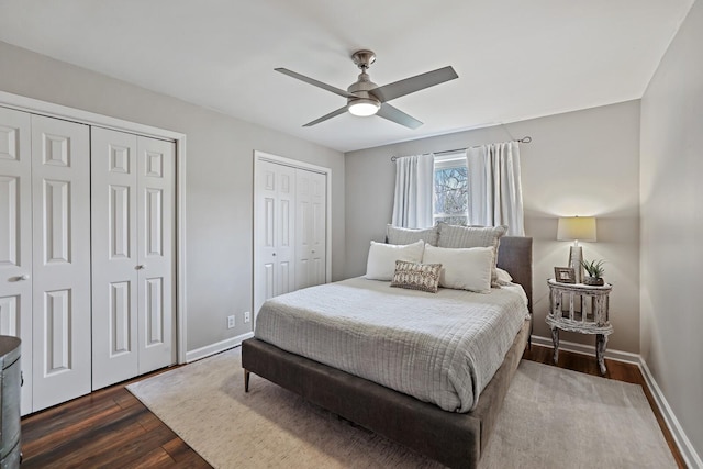 bedroom with a ceiling fan, dark wood-type flooring, baseboards, and multiple closets