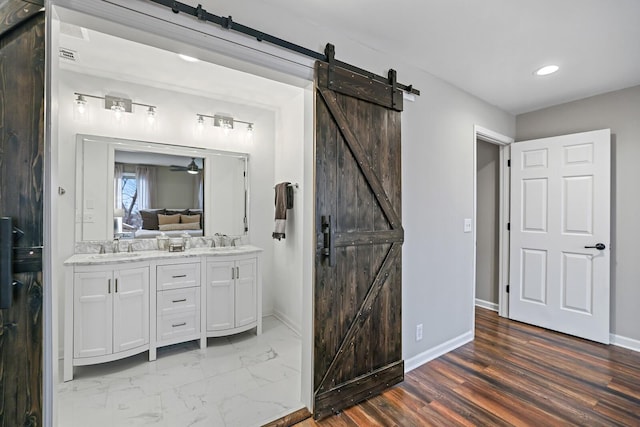 ensuite bathroom featuring baseboards, double vanity, a sink, marble finish floor, and connected bathroom