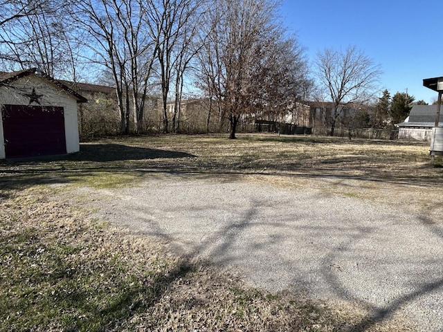 view of yard featuring a garage, driveway, and an outdoor structure