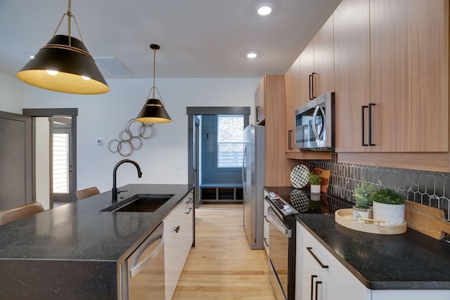 kitchen with an island with sink, light wood-type flooring, plenty of natural light, stainless steel appliances, and a sink