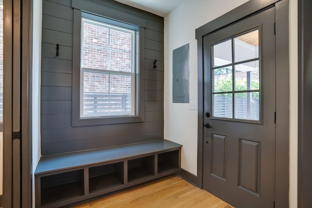 mudroom featuring light wood finished floors, wooden walls, and electric panel