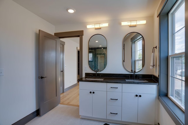 bathroom featuring double vanity, recessed lighting, and a sink