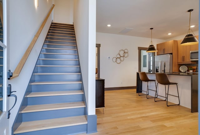 staircase with recessed lighting, wood finished floors, and baseboards