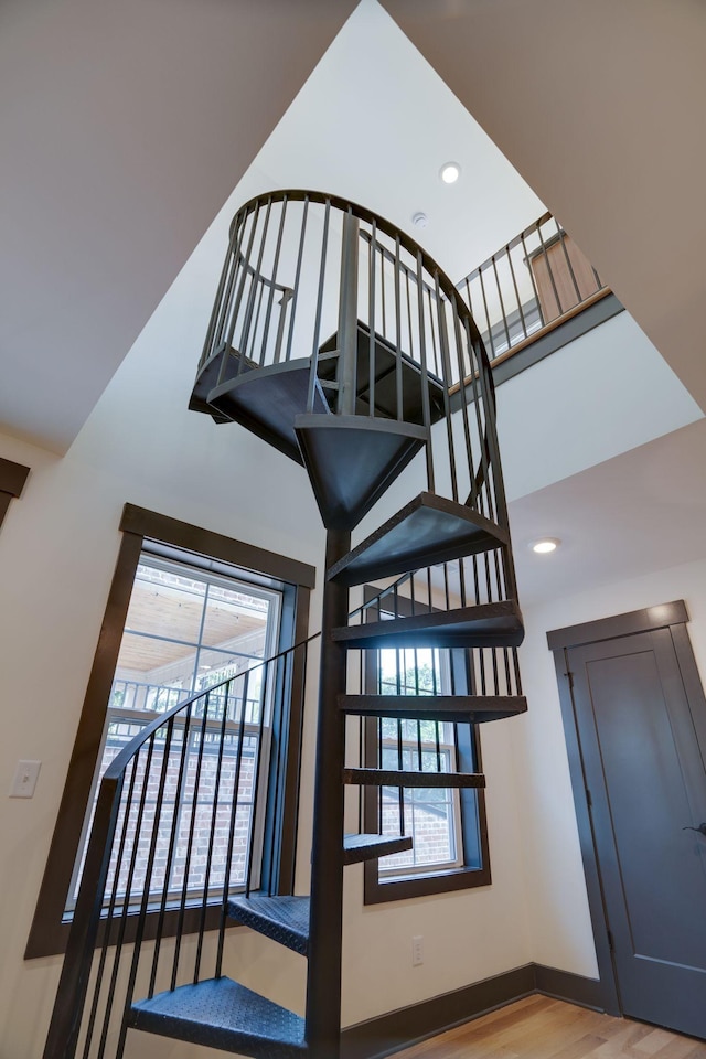 staircase with recessed lighting, baseboards, a towering ceiling, and wood finished floors