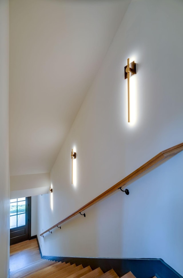 staircase with lofted ceiling and wood finished floors