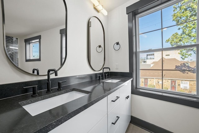 full bath with double vanity, baseboards, and a sink