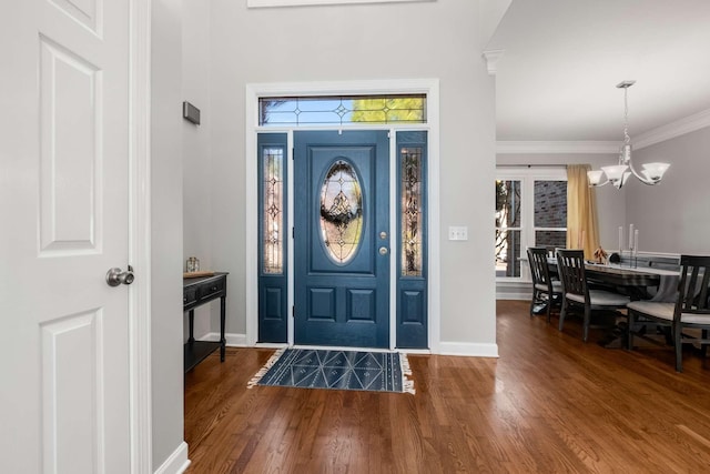 foyer featuring ornamental molding, wood finished floors, baseboards, and a chandelier