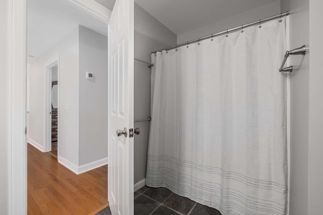 full bathroom featuring curtained shower, baseboards, and wood finished floors