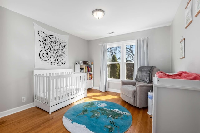 bedroom with visible vents, wood finished floors, and baseboards