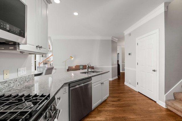 kitchen featuring light stone counters, a peninsula, a sink, ornamental molding, and stainless steel appliances