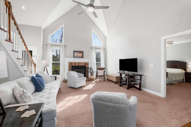 carpeted living room with a wealth of natural light, a fireplace, high vaulted ceiling, and stairs