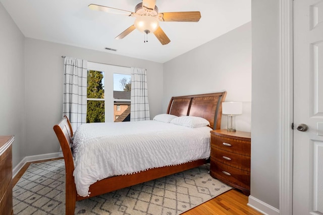 bedroom featuring visible vents, baseboards, a ceiling fan, and light wood finished floors